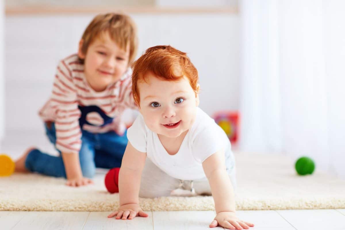 portrait of happy redhead infant baby boy crawling on the floor at home