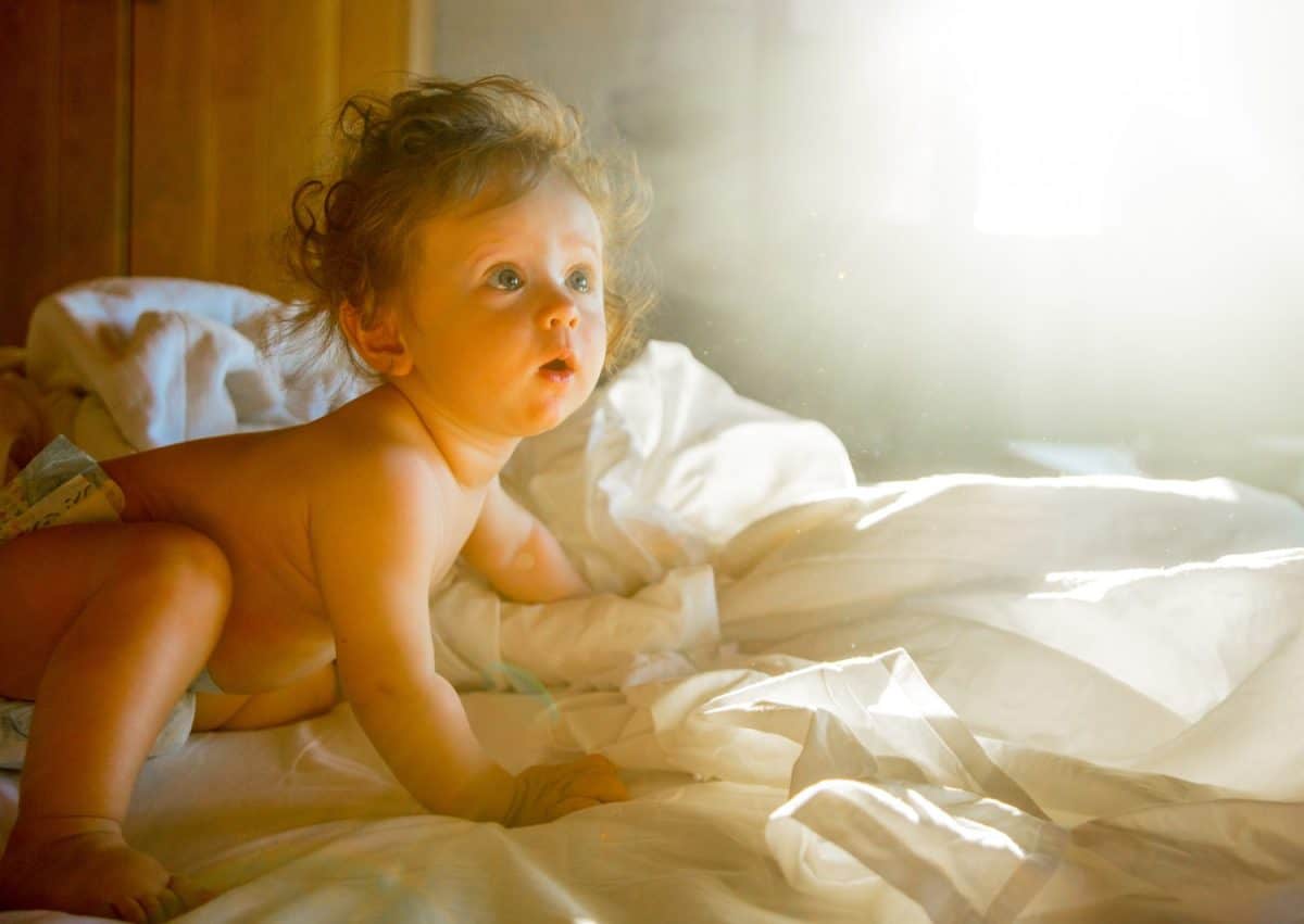 Little baby boy in a bed in a morning time. Interior in Crete style, Greece