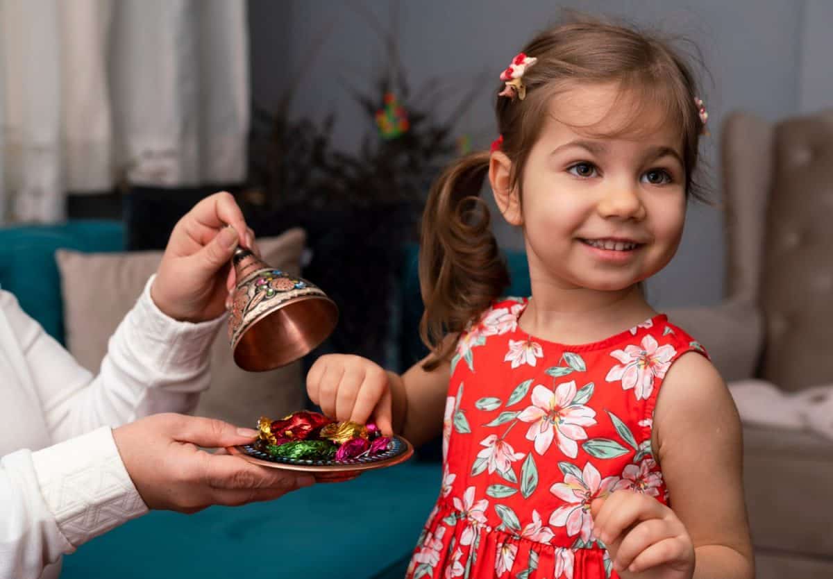 Portrait of cute baby girl holding candies from during Ramadan feast (aka: Ramazan or Seker bayrami). Sweets in little child hands as a tradition in middle eastern culture.