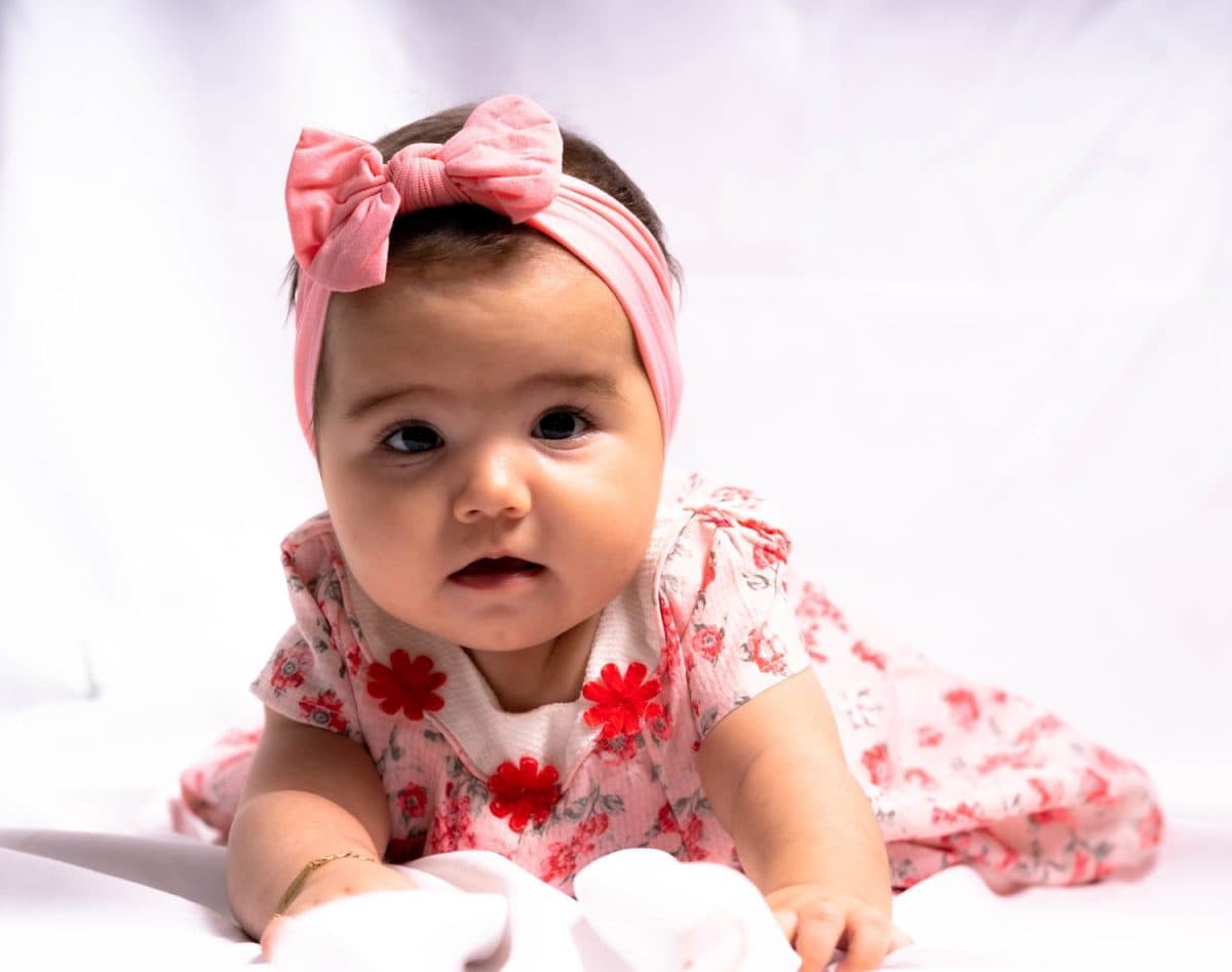 A Spanish kid with pink dress and headband on white background