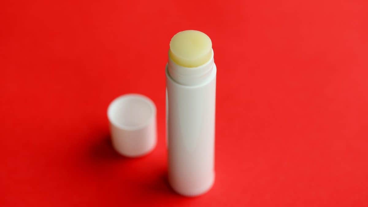 Lip balm isolated on red background. White chapstick.