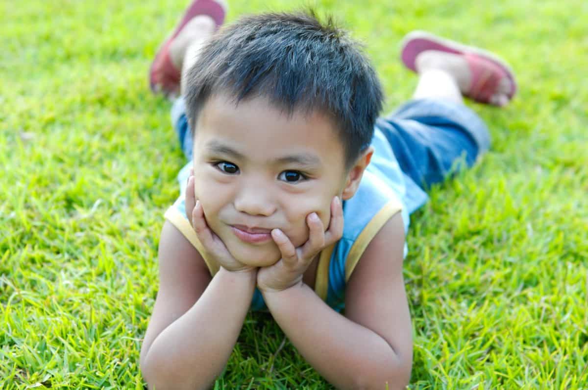 Little boy lying on a green grass