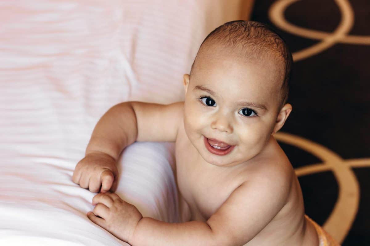 Sweet baby boy near bed in the hotel room. Family vacation with children