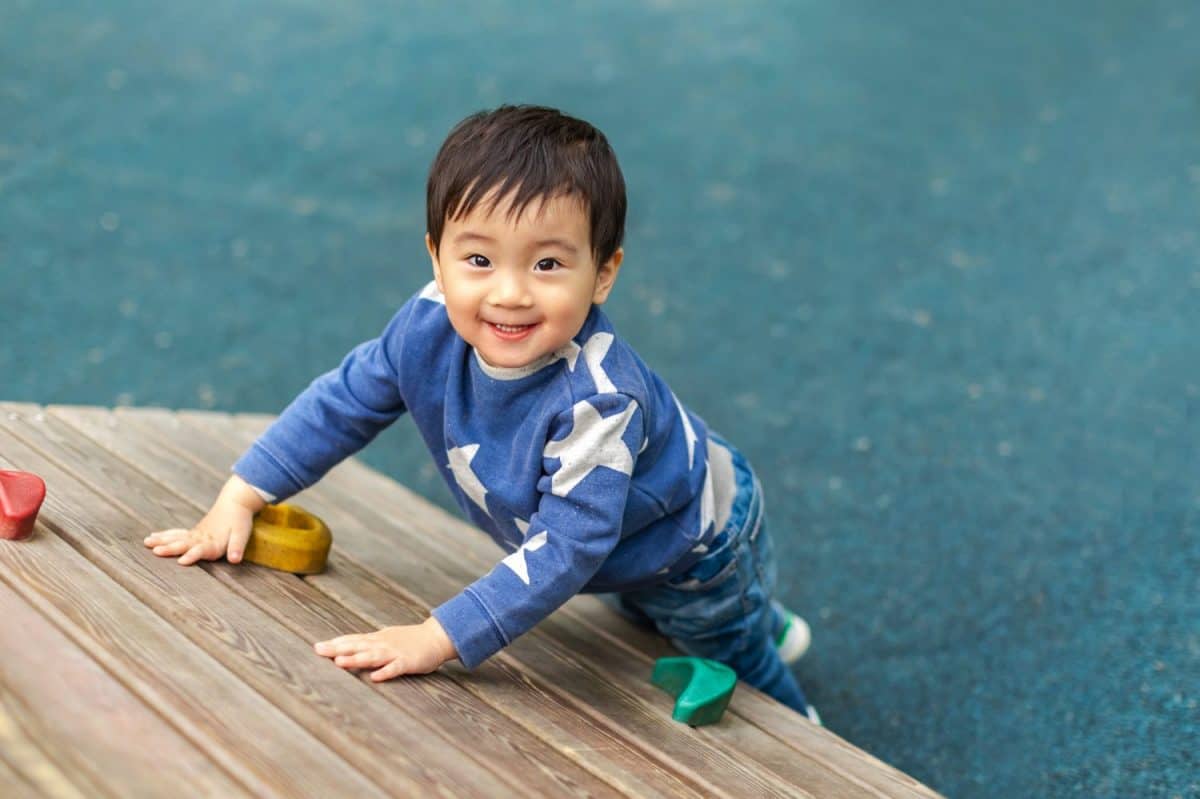 Asian boy is playing in playground with happy face in summer. Copy space for text