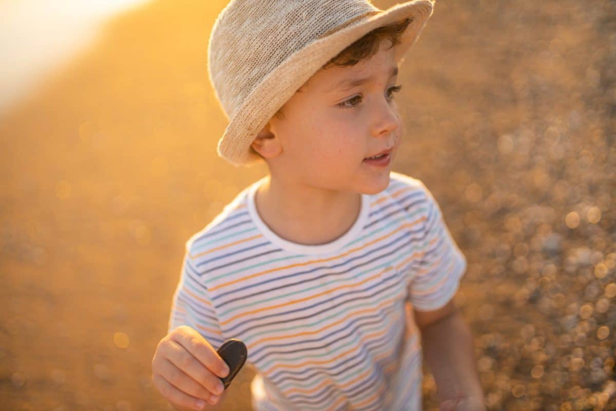 Todler plays with sea pebbles. a boy runs along the seashore and plays with stones. Rest at the sea. Todler will develop and rest. Happy childhood moments.