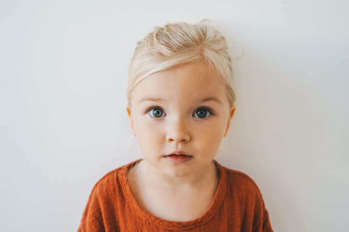 Child girl cute blonde hair baby at home toddler looking at camera portrait 3 years old kid family lifestyle