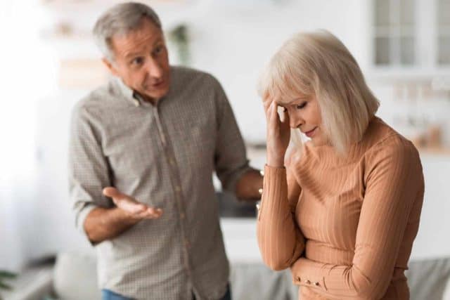 Domestic Abuse. Aggressive Senior Husband Shouting At Wife Having Quarrel Standing In Kitchen At Home. Selective Focus On Unhappy Woman. Marital Crisis And Relationship Problems Concept