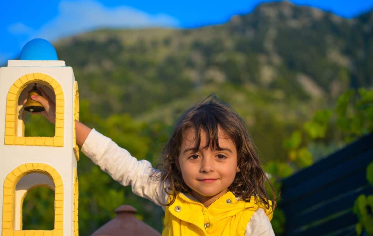 Happy child touching a miniature house in a Greek Island.