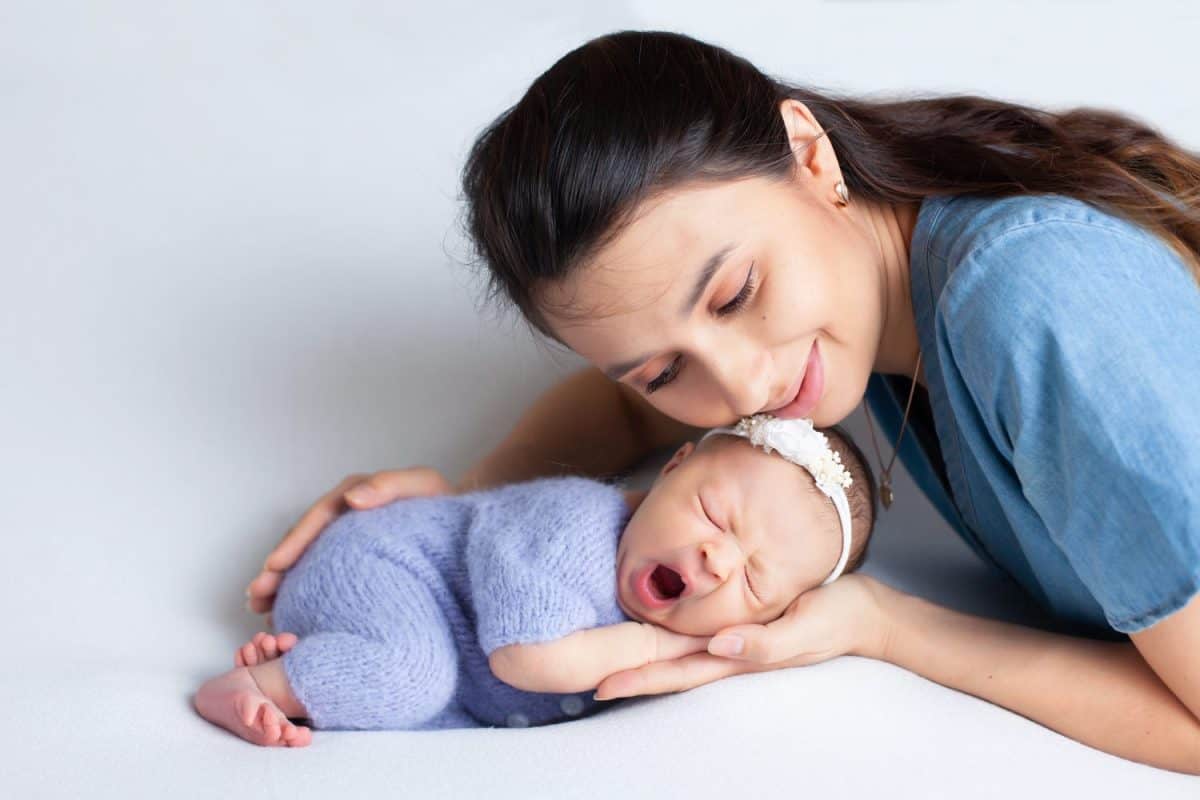 Beautiful young mother with a newborn daughter in a diaper on a white background. Motherhood. Tenderness. Space for text.