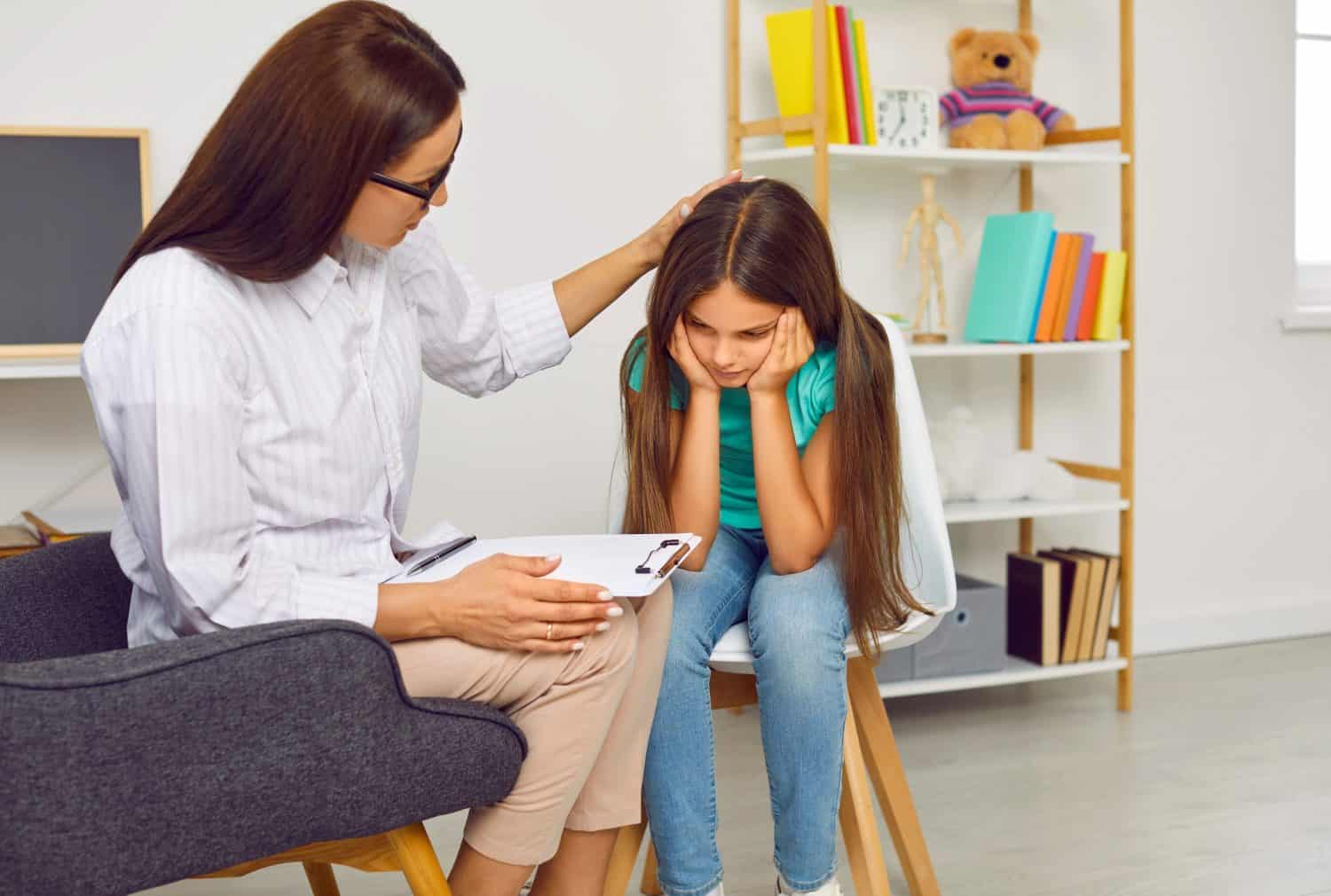 Professional psychologist working with sad, depressed little child. Supportive therapist or school counsellor helping stressed teenage girl who has anxiety issues and troubles with social interaction