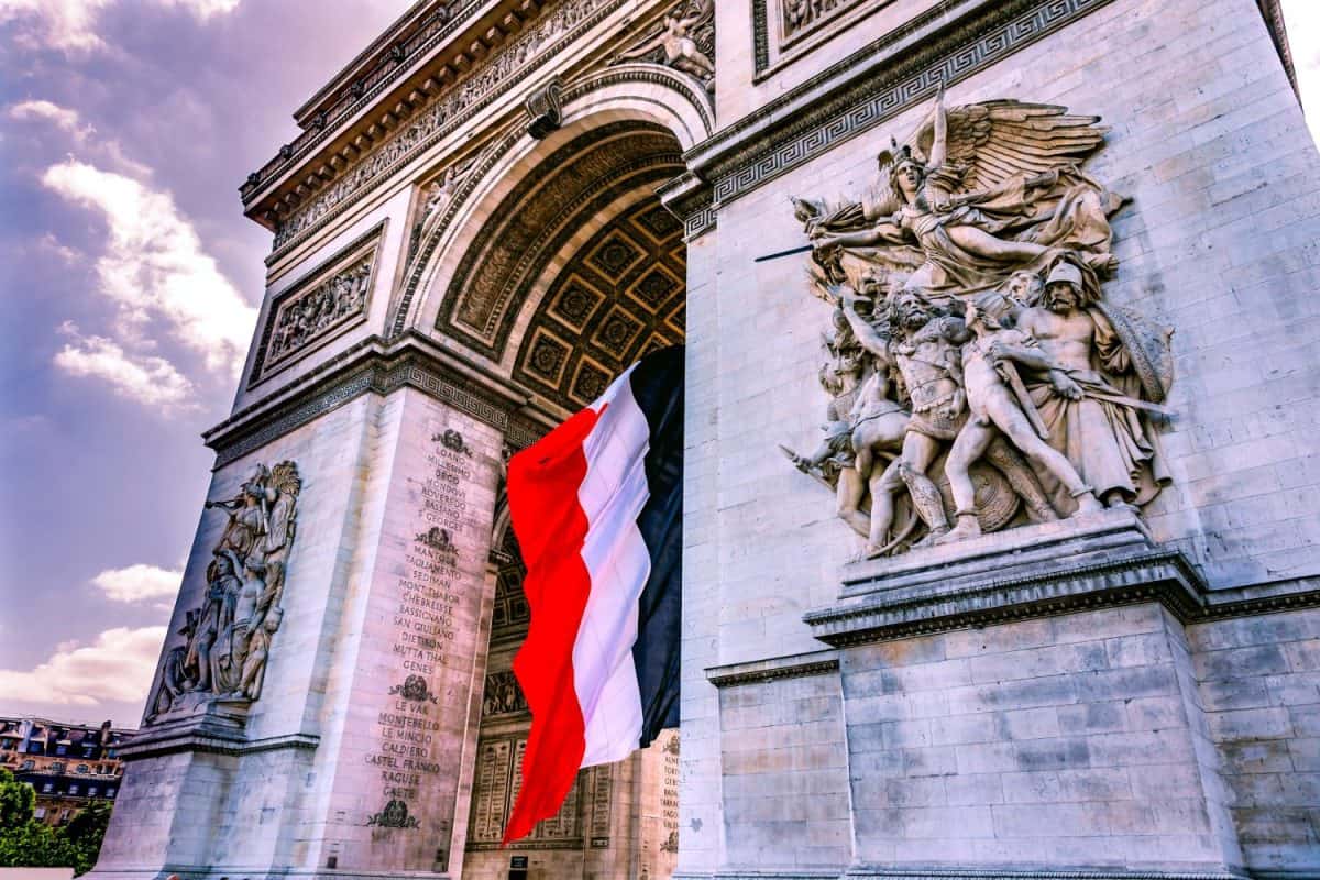 Arc de Triomphe and French flag, Paris, France. Completed in 1836 monument to the dead in the French Revolution and Napoleonic Wars. Includes Tomb to Unknown Soldier