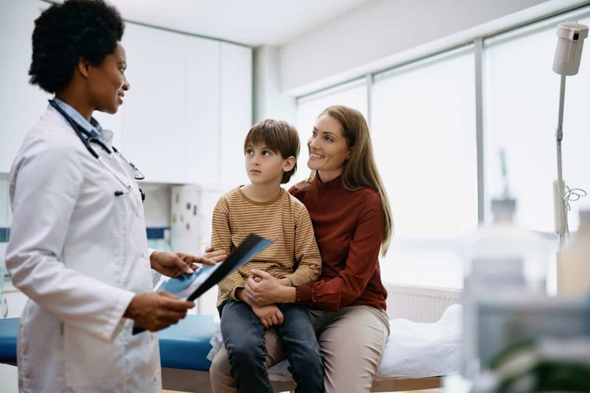 Little boy and his mother communicating with black female doctor at pediatrician's office.