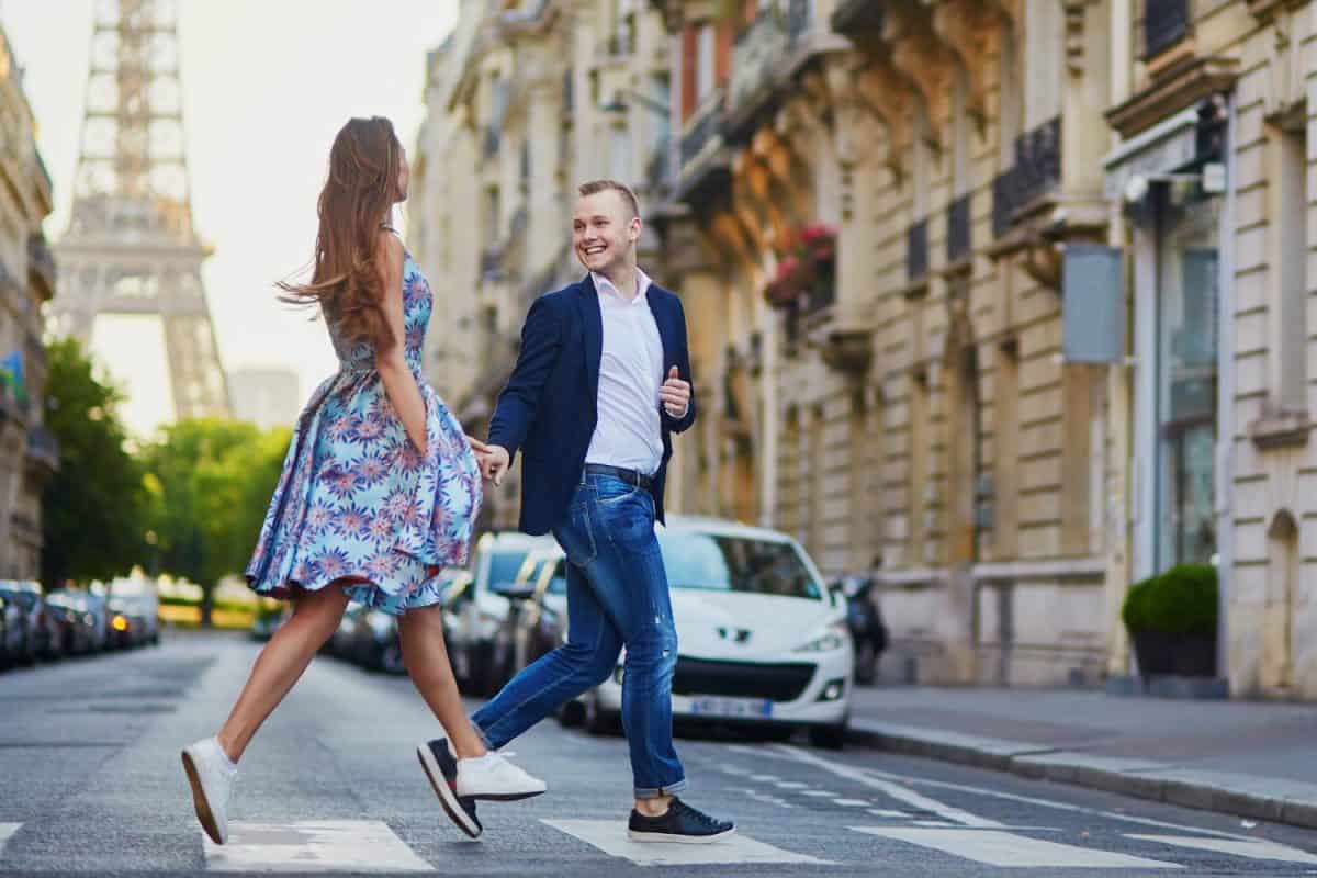 Romantic couple running across the street with Eiffel tower in background in Paris, France