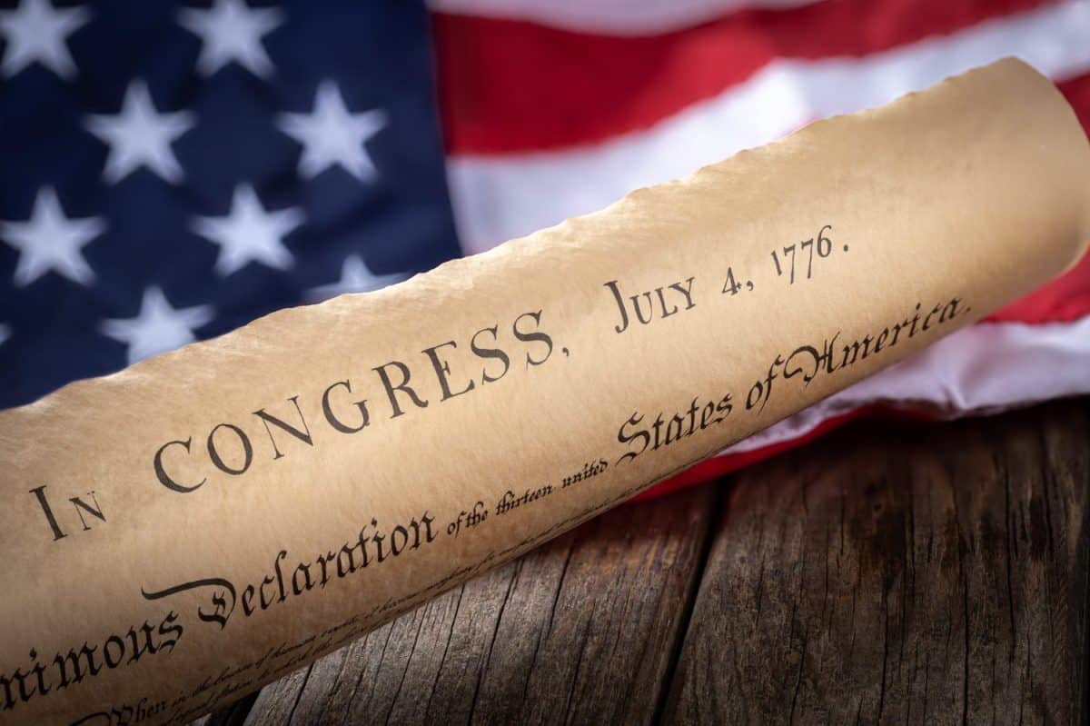 United States declaration of independence with American flag in background on rustic wooden table