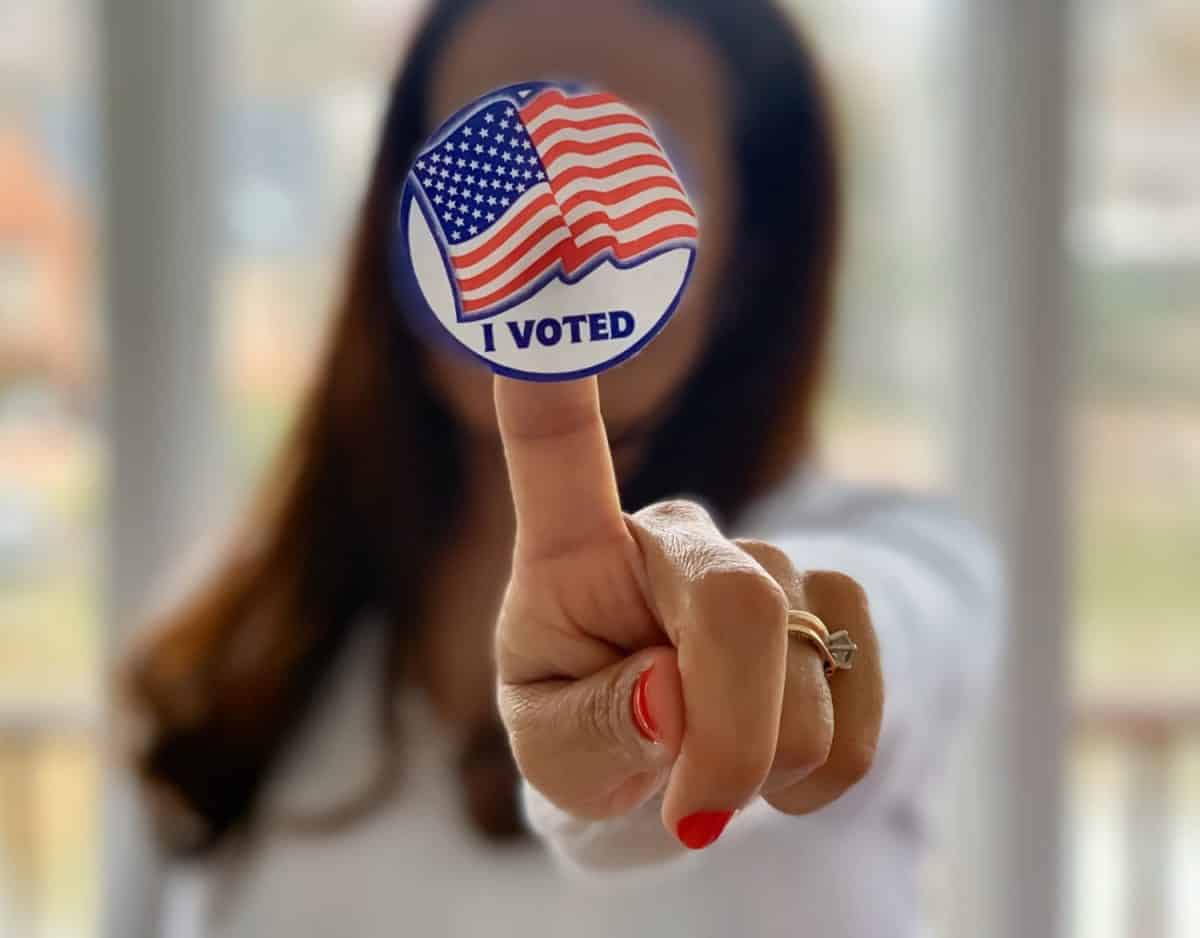 Selective focus of an I voted sticker being hold by a Hispanic Latino woman in her finger after exercising her citizen civil right and duty during elections day.