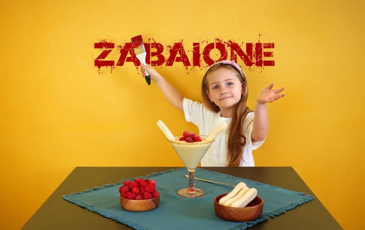 Cute little baby girl celebrating at home and posing funny at the table with traditional Italian dessert zabaione.