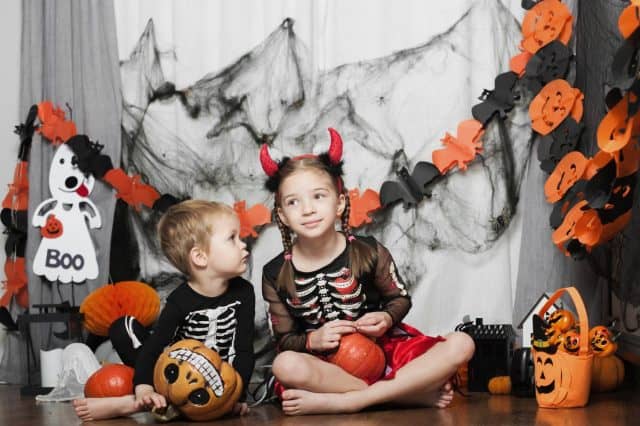 Children boy and girl with pumpkin fooling around at home on Halloween