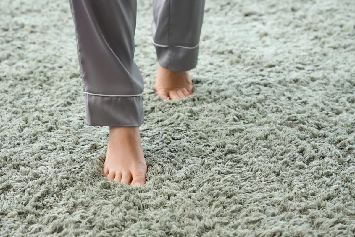 Barefoot woman walking on green carpet at home, closeup. British Household Routines That Confuse Americans