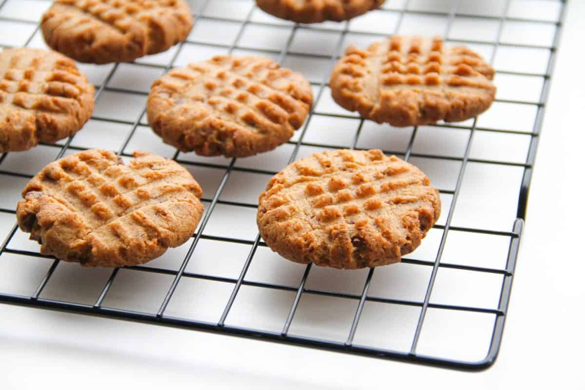 Process of making peanut butter cookies. Peanut butter cookies are cooling after baking on a rack on a white background.