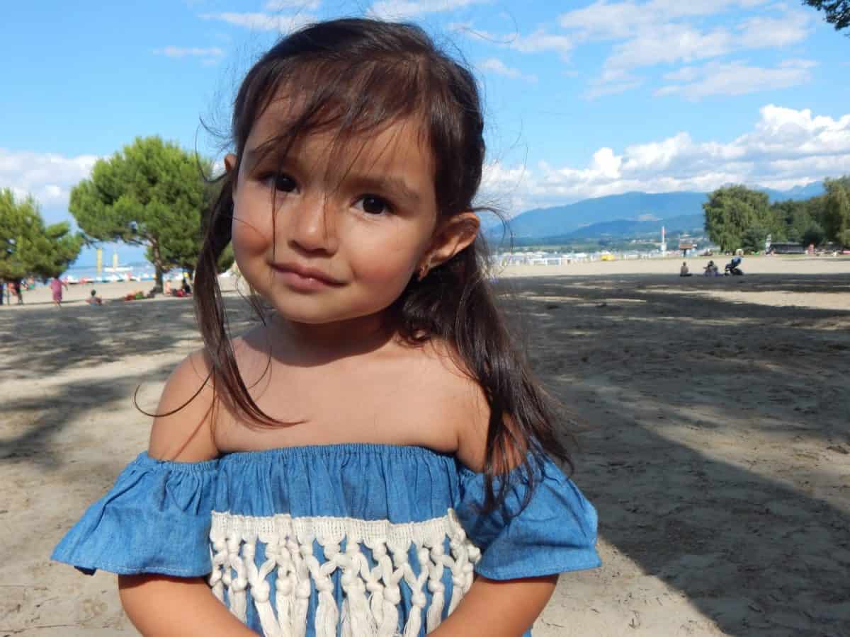 Cute little girl in summer suit (tropical poncho with fringes)