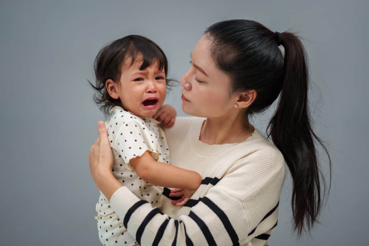 mother holding and comforting her crying toddler baby