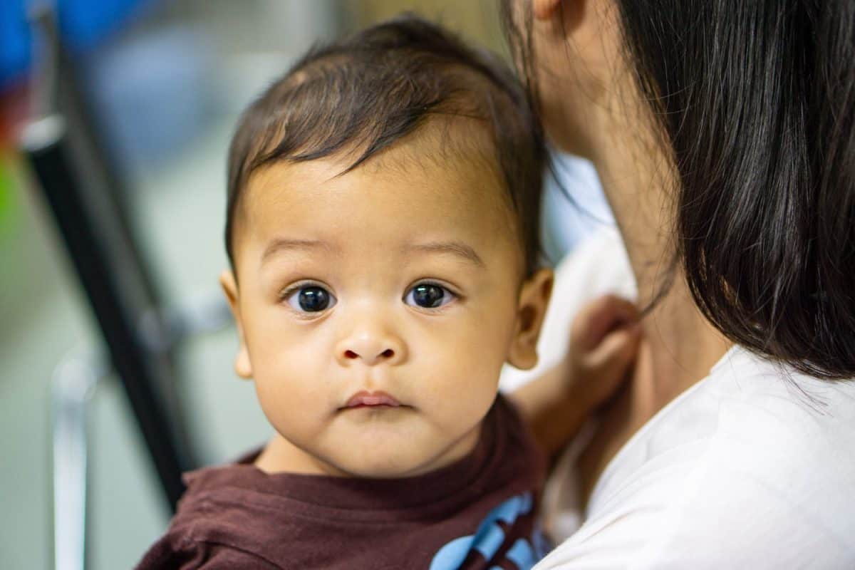 Closeup Portrait of a Baby Boy with Dark Hair and Big Brown Eyes Looking at the Camera.