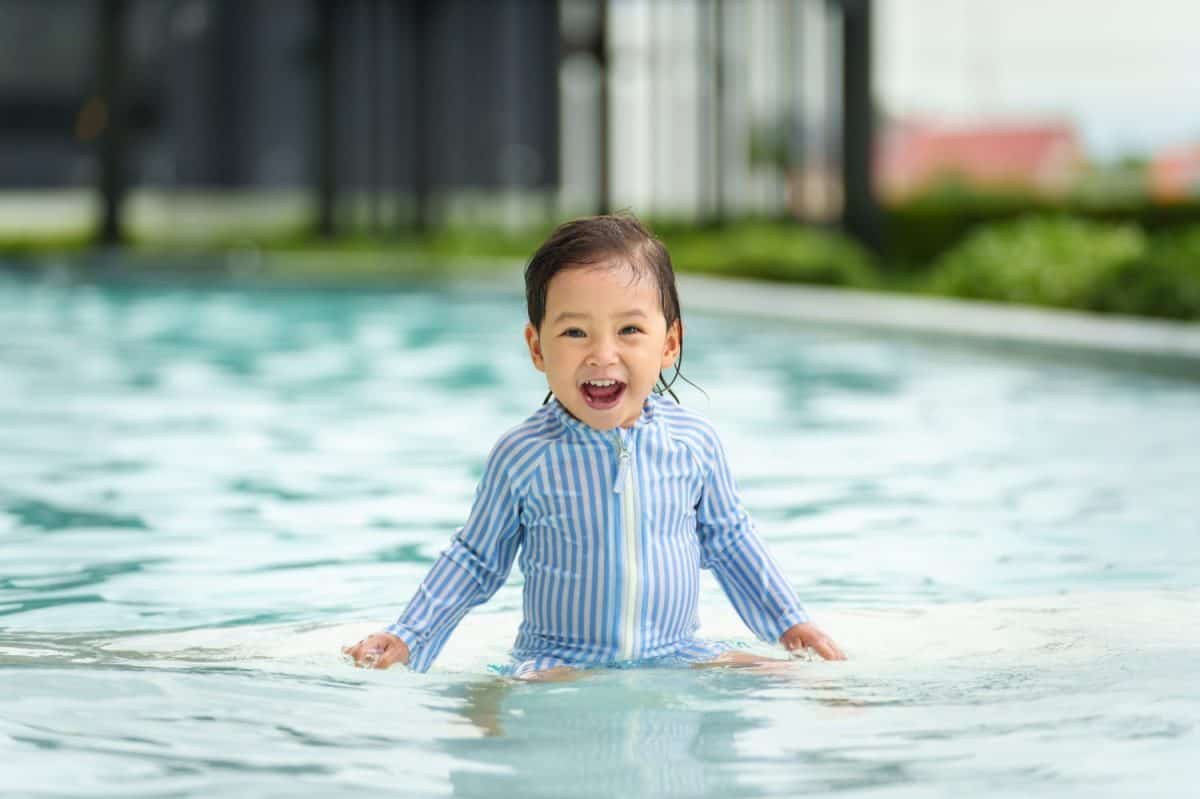 happy toddler baby playing water in the swimming pool