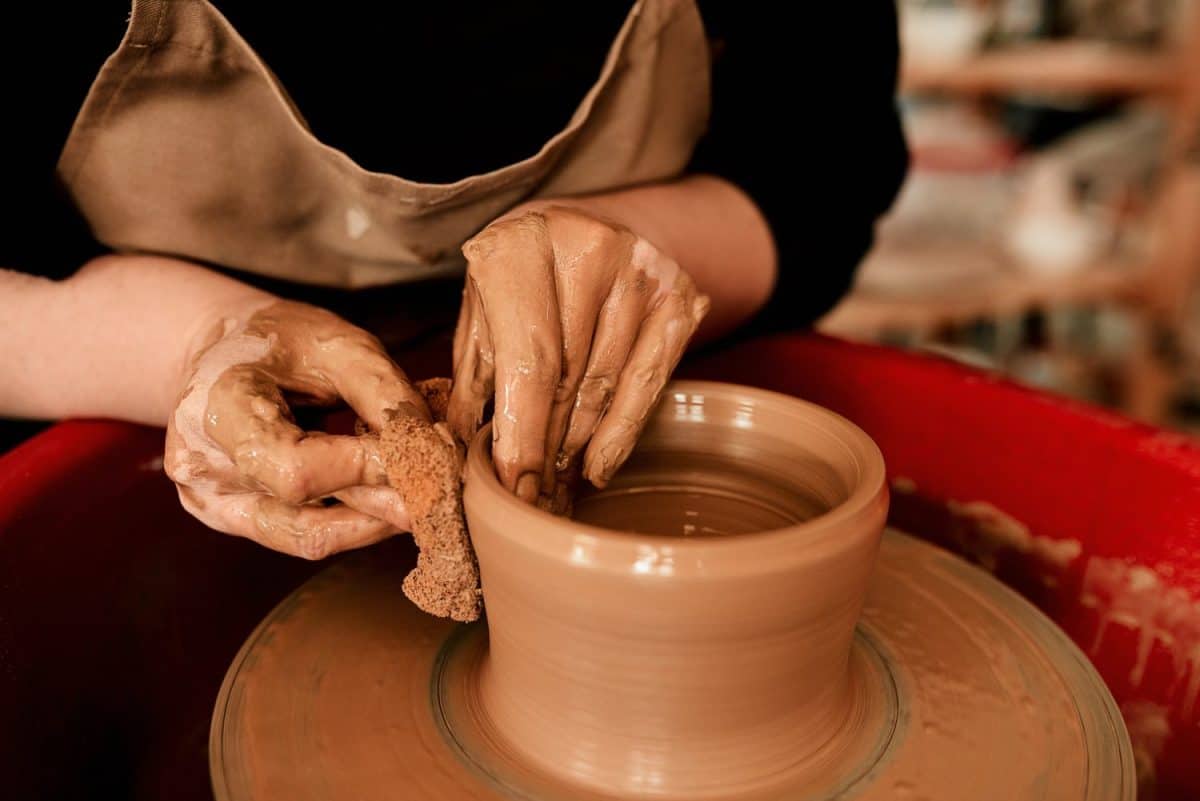 Hands, clay and pottery wheel with skills for craft, tools or sustainable production at small business. Person, artist and entrepreneur for eco friendly material, sculpture or manufacturing in studio. Things to stop dong once you hit 30