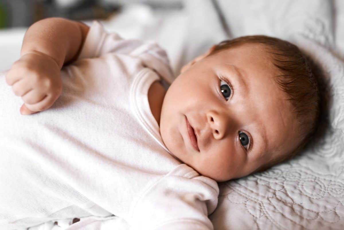 Baby, portrait and kid on bed with relax for wellness, child development or comfortable in bedroom. Young, newborn and infant boy in nursery for curiosity, growth or morning routine in home.