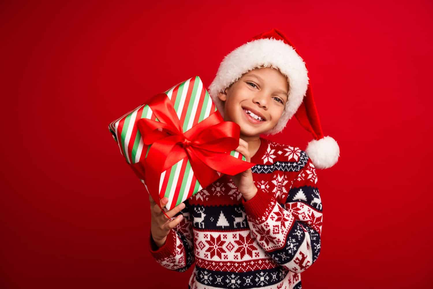 Photo portrait of cute little boy hold present box celebrate christmas wear knitwear sweater isolated on red color background