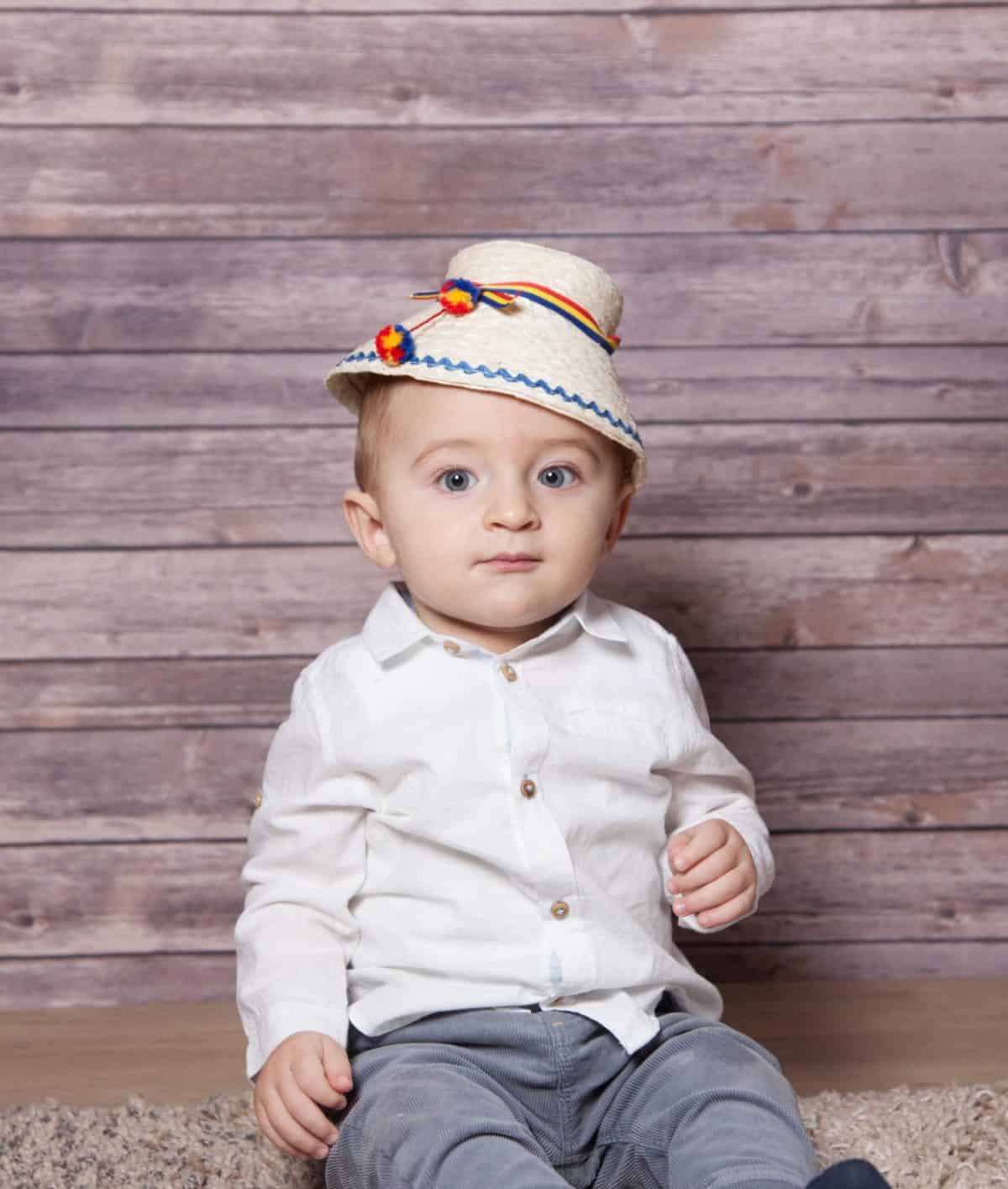 Portrait of a 1 year old baby boy wearing a Romanian traditional hat.