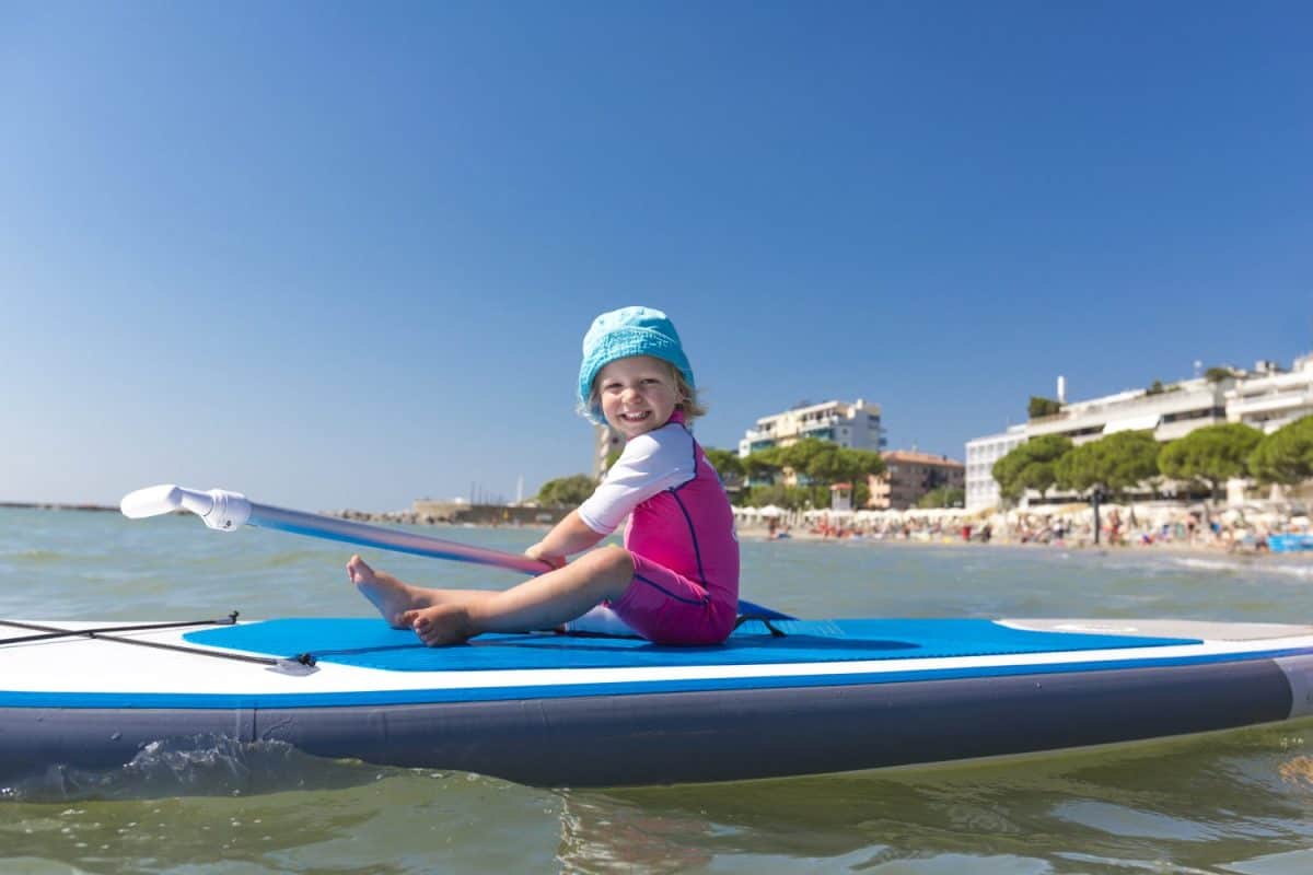 Toddler sitting on a surfboard smiling