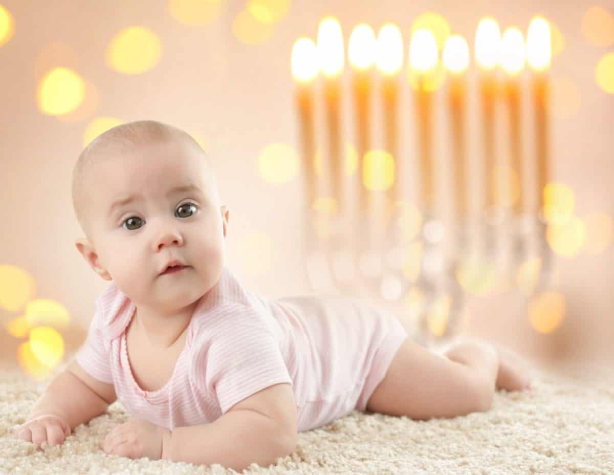 Little child on blurred festive lights background. Baby's First Hanukkah