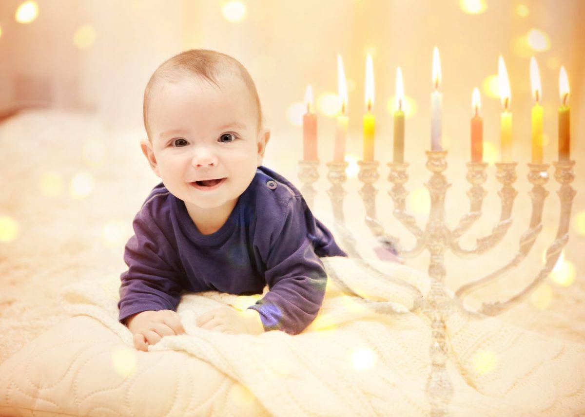 Little child on blurred festive lights background. Baby's First Hanukkah