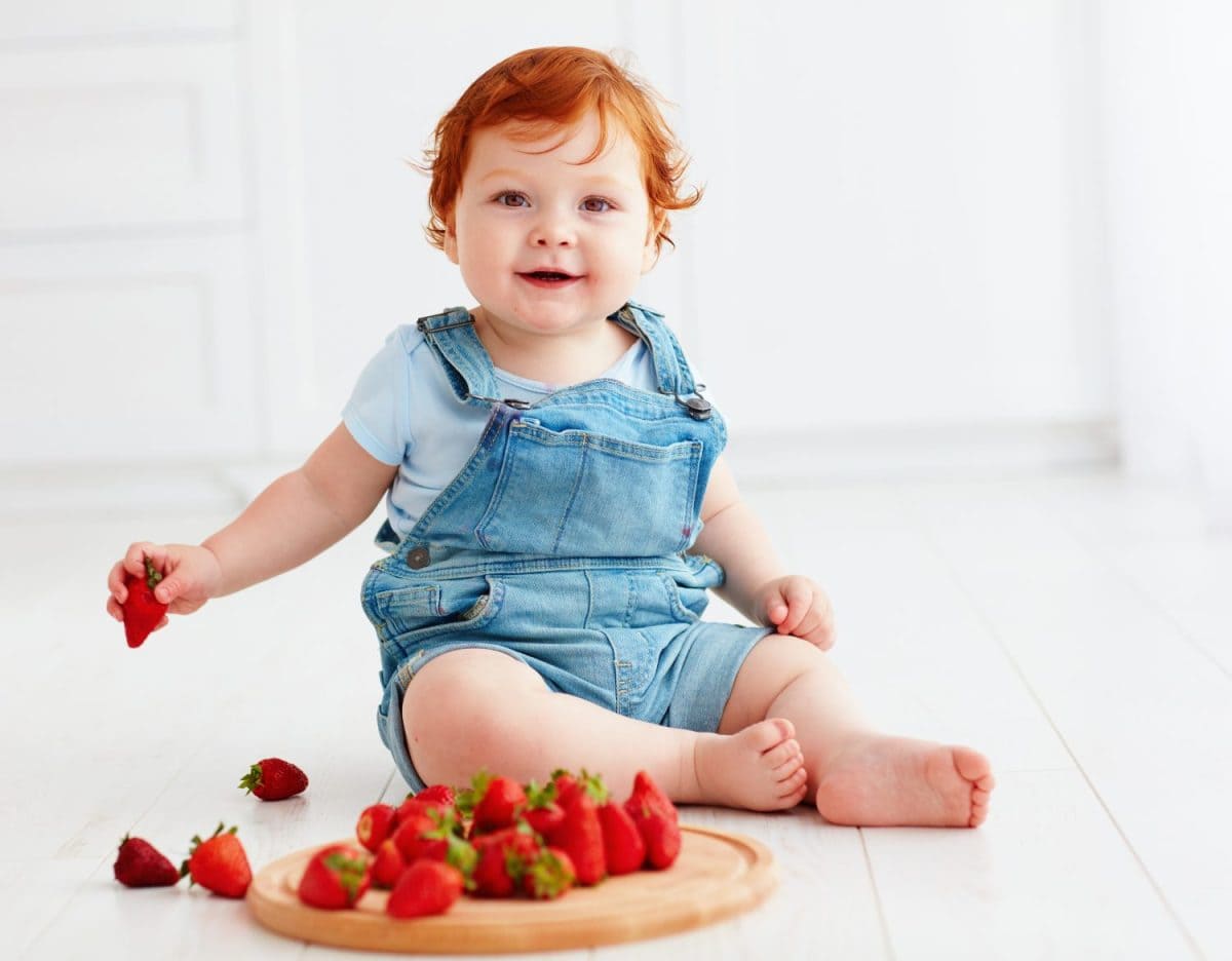 cute ginger toddler baby tasting strawberries