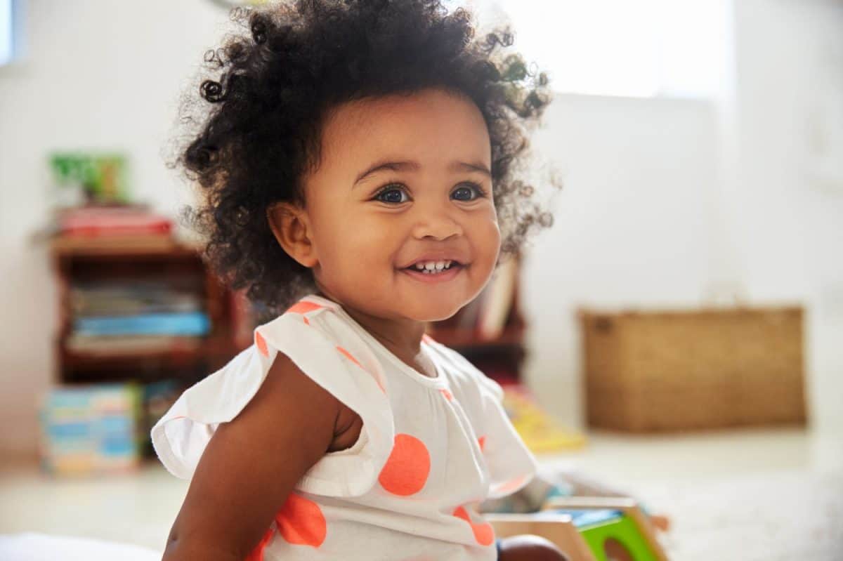 Happy Baby Girl Playing With Toys In Playroom