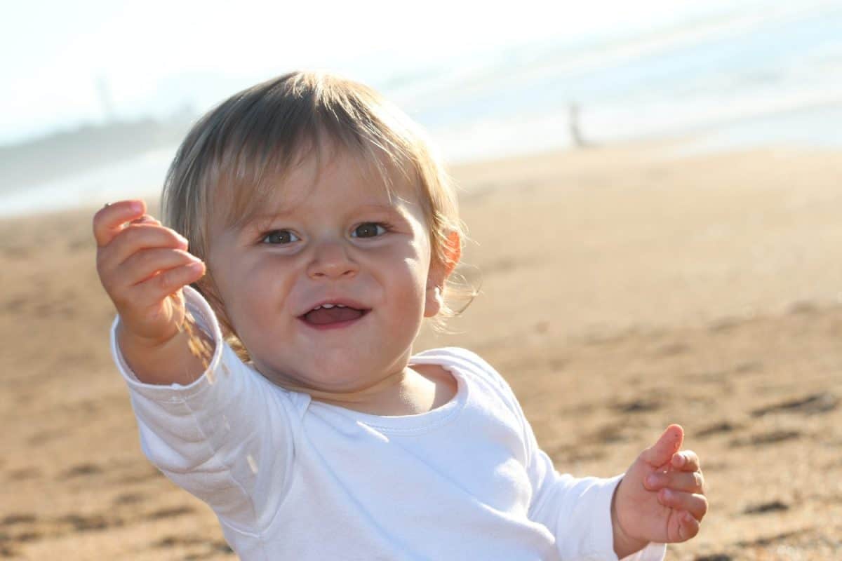 Happy blond baby playing at the beach