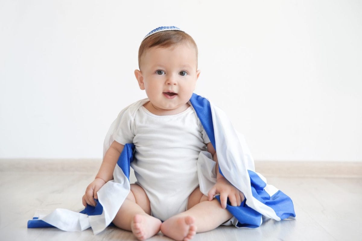 Cute baby with flag of Israel sitting on floor at home