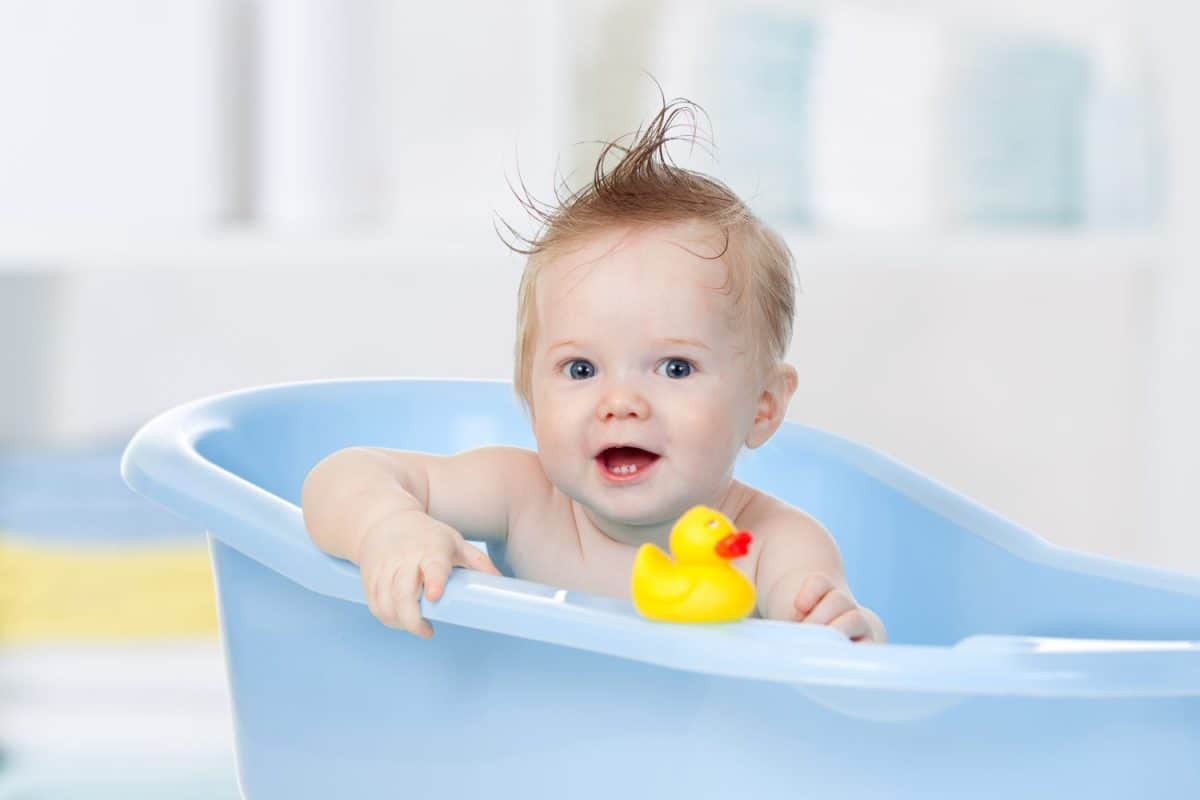 adorable baby boy taking bath in blue tub