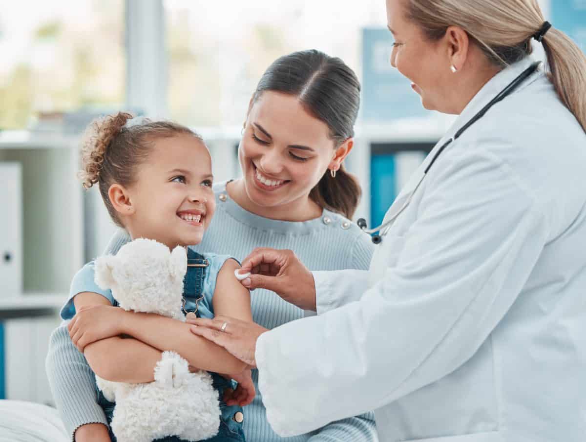 Shes not afraid to get her routine vaccine. a doctor using a cotton ball on a little girls arm while administering an injection in a clinic.