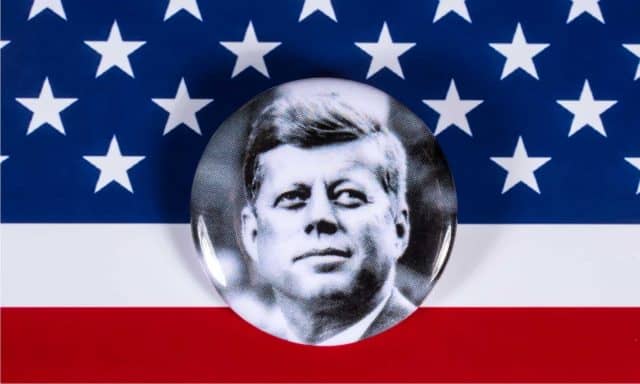 A John F. Kennedy badge pictured over the USA Flag