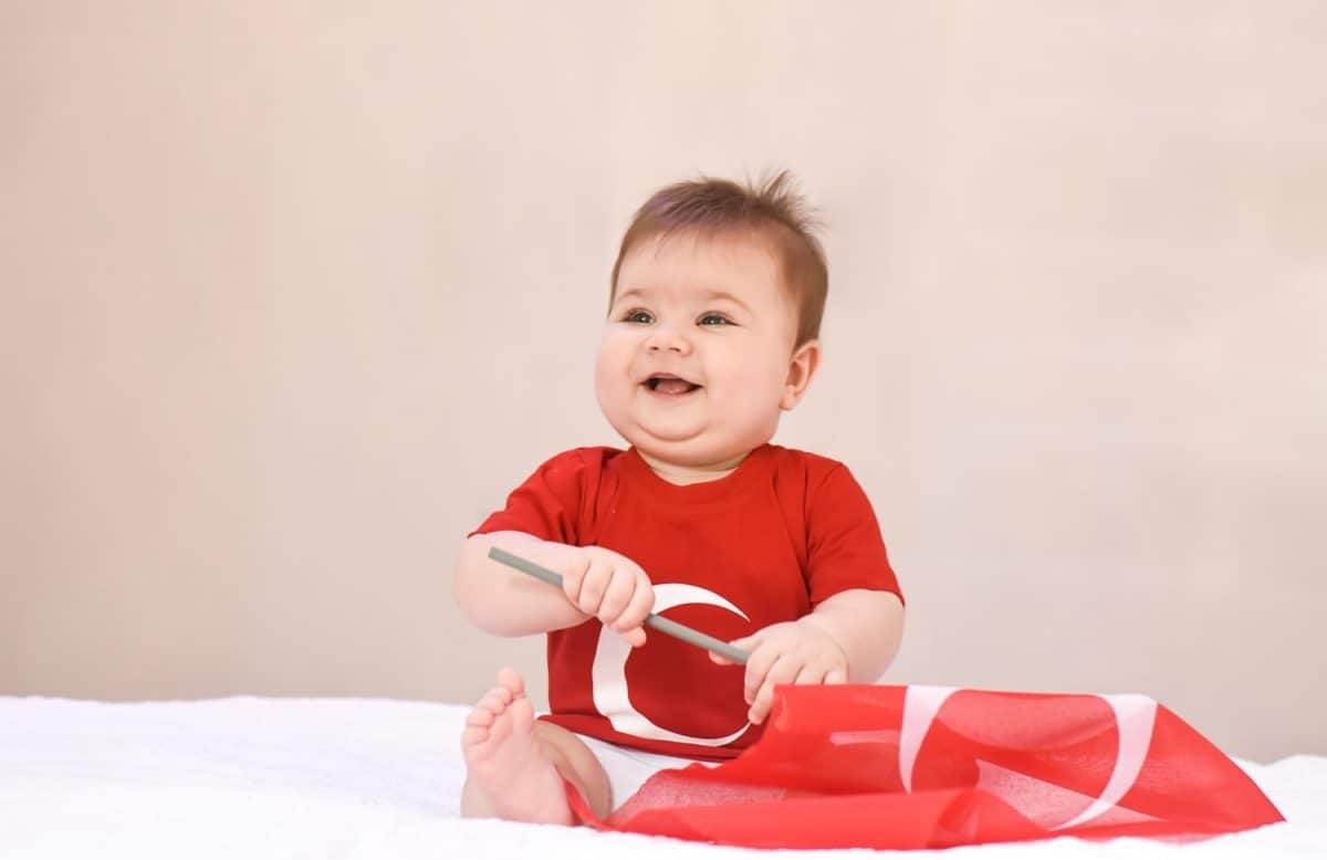 Happy, little kid, cute baby with Turkish flag t-shirt and holding Turkish flag on white background. Patriotic holiday.