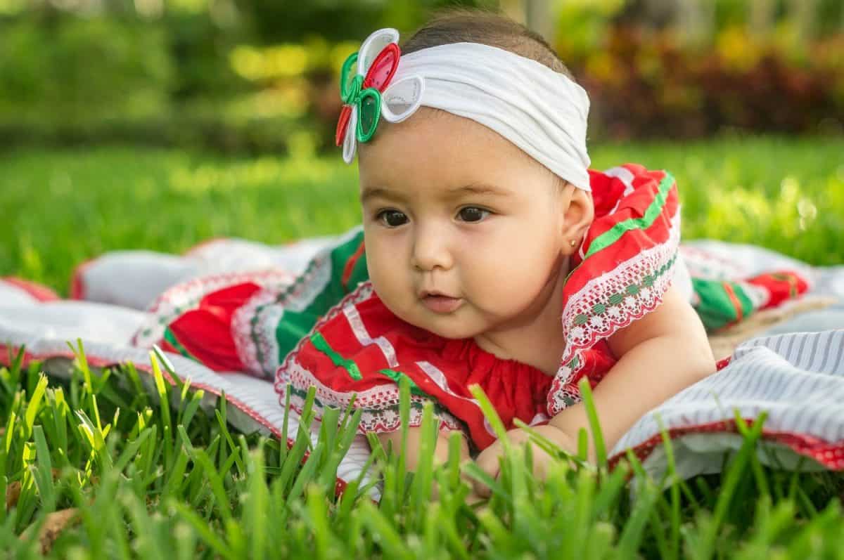 Beautiful baby, Mexican dress, patriotic colors, nice, tender emotions, lying on the grass, sitting on the grass, on pink carpet, playing in the garden,