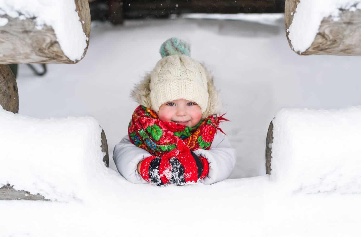 Russian baby girl wearing a hat with a fur hat and warm mittens. Horizontal portrait