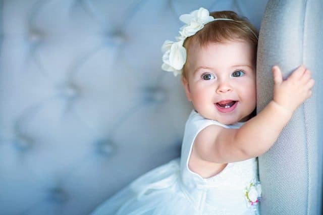 Image of sweet baby girl in a wreath, closeup portrait of cute 8 month-old smiling girl, toddler.Studio shooting