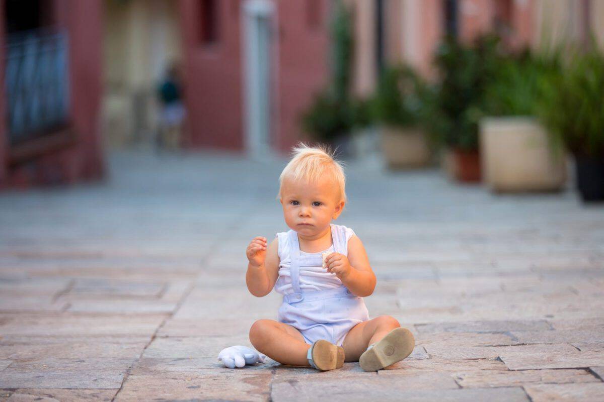 Baby child, boy, sitting on colorful street in the town of Villefrance, French Riviera