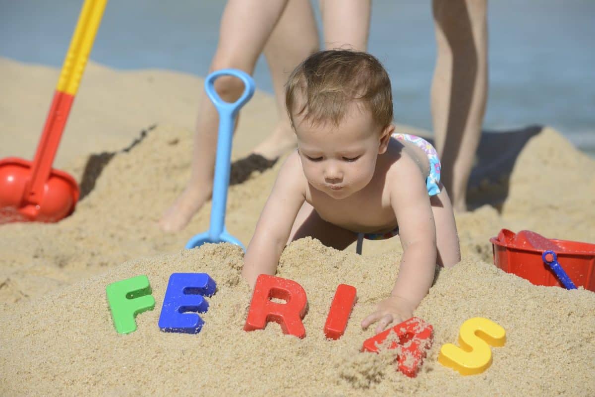 Summer vacation: Baby playing with beach toys in the sand