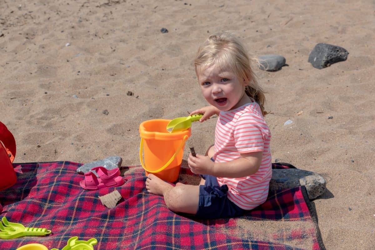 Portrait of a female infant playing in the sand at the beach.