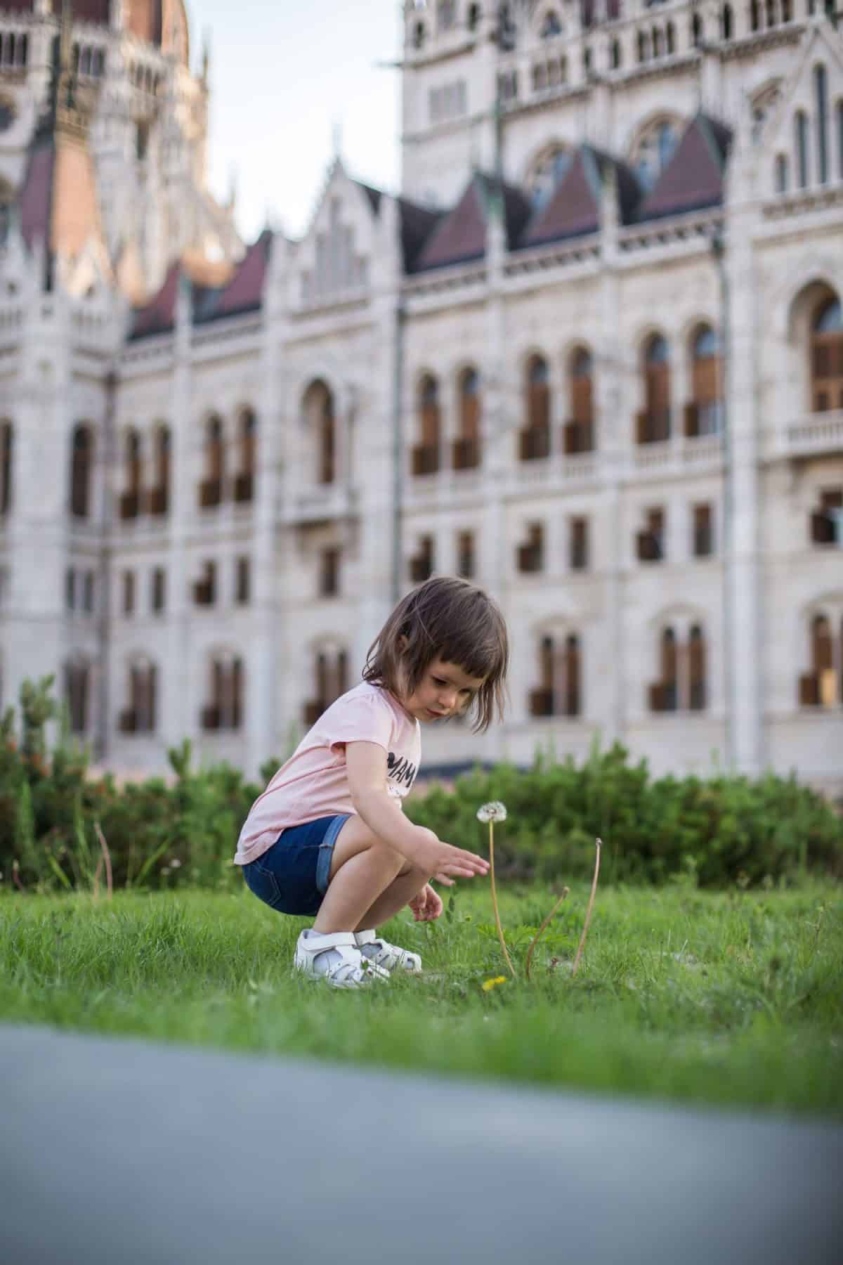 little girl child in shorts and a t-shirt stands near the Hungarian Parliament in Budapest