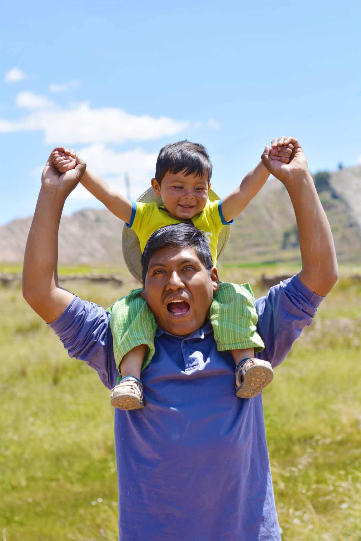 Native american man with his little son on shoulders in the countryside.